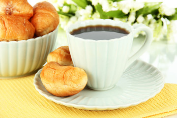 Tasty croissants and cup of coffee on table on white background