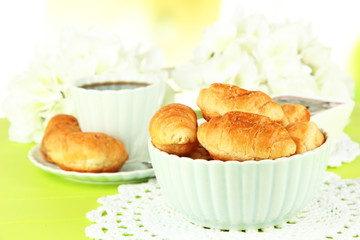 Tasty croissants and cup of coffee on table close-up