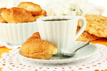 Tasty croissants and cup of coffee on table close-up