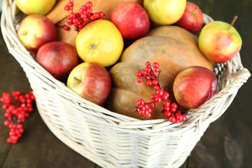 Juicy apples and pumpkin in wooden basket on table close-up