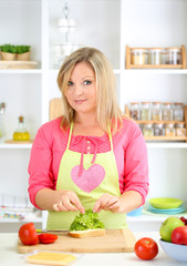 Happy smiling woman in kitchen preparing  sandwich