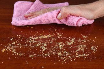 Hand wiping wooden surface with pink rag