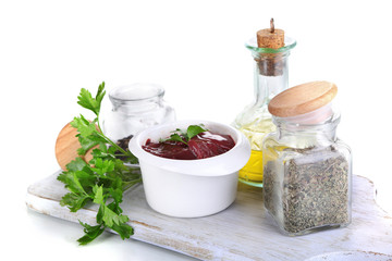 Raw liver in bowl with spices and condiments isolated on white