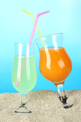Beach cocktails in sand on blue background