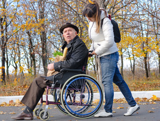 Woman pushing an elderly man in a wheelchair