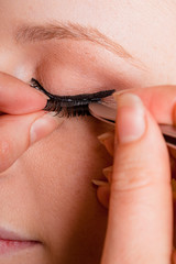 Professional makeup artist artist applies false eyelashes