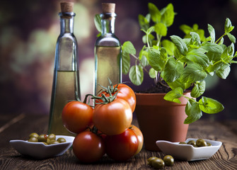 Bottles of olive oil, bunch of tomateos, fresh basil and olives
