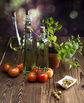 Bottles of olive oil, bunch of tomatoes, herbs, olives