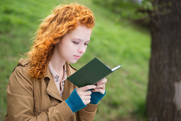 Young beautiful woman in park reading a book.