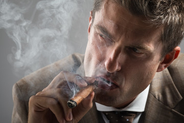 hard gaze businessman while smoking a cuban cigar