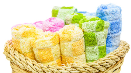 Rolls of different colors of towels in a wicker basket.
