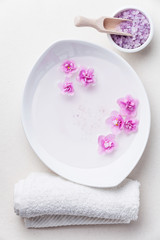 Obraz na płótnie Canvas Flowers in white bowl with sea ​​salt for SPA