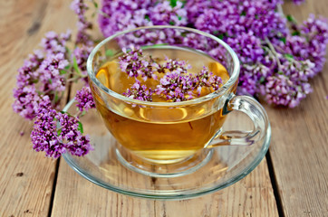 Fototapeta premium Herbal tea from oregano in a glass cup on a board