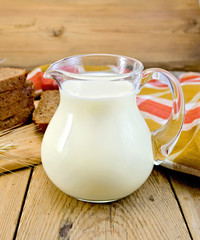 Milk in a jug with rye bread and red napkin