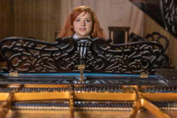 The red-haired girl sits at a grand piano