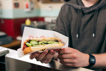 salesman with hotdog in fast food snack bar