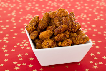 Burnt almonds in white dish on red background