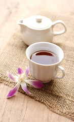 cup of tea with beautiful orchid over wooden background