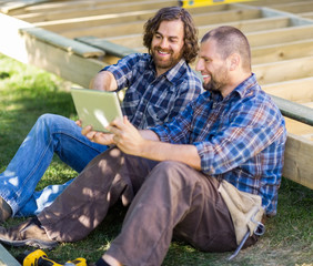 Happy Carpenters Using Digital Tablet At Construction Site