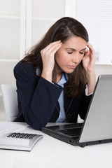 Burnout - Frau hat Migräne - sitzend am Schreibtisch; Arbeit
