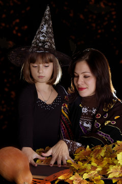 Witch child and mother makong magic on halloween
