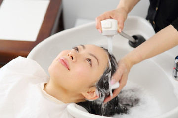 Obraz na płótnie Canvas シャンプー台で髪を洗う女性
