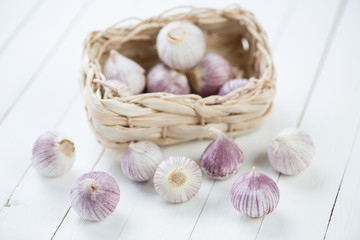 Wicker tray with chinese solo garlic on white wooden boards © Nickola_Che