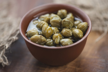 Pickled capers in a ceramic dish, studio shot