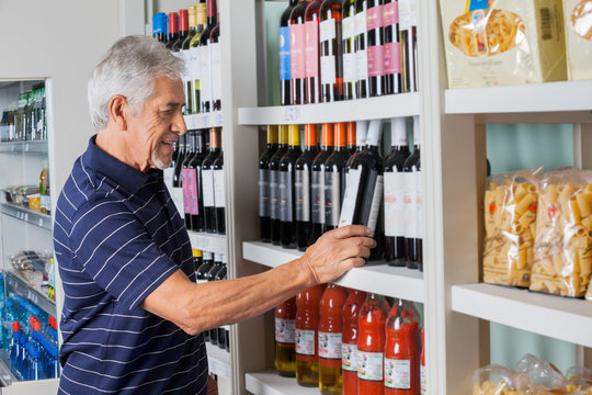 Senior Man Choosing Wine At Supermarket
