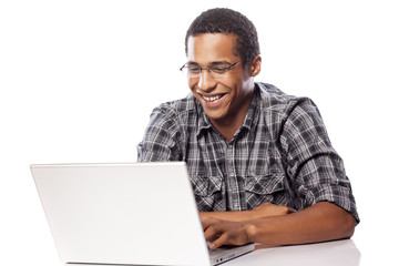 happy and smiling dark-skinned student working on his laptop
