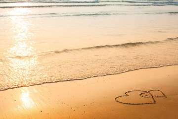 Hearts drawn on the sand of a beach, soft wave of the sea