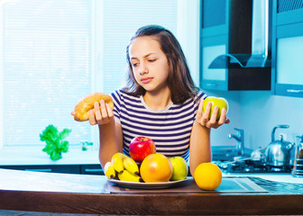 Obraz premium Beautiful Young Woman choosing between Fruits and Sweets