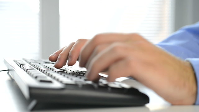 closeup of male hands typing on keyboard