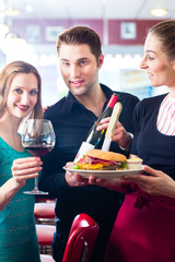 People in American diner with burger and wine