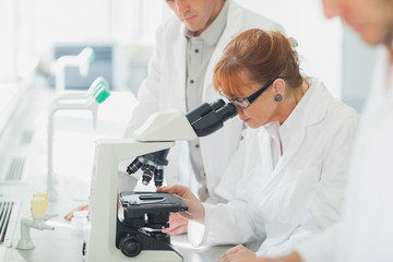 Woman standing looking through microscope