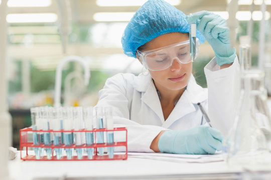 Student holding test tube and taking notes