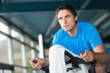 Determined young man working out at spinning class