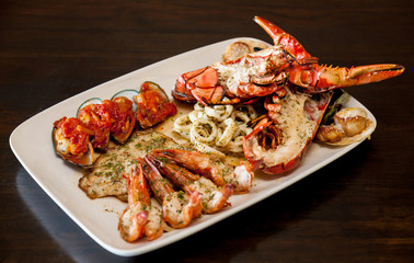 Grilled red lobster and seafood on platter.