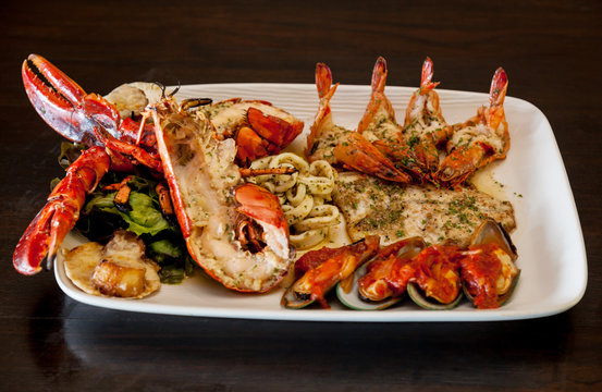 Grilled red lobster and seafood on platter.