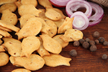 Delicious crackers with onion and spices on wooden background