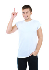 Fototapeta premium Smiling young man in white t-shirt pointing upward with index finger, casual fashion and advertising