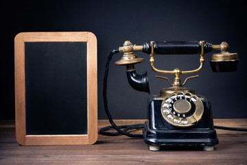 Vintage old telephone, black board frame on wood table