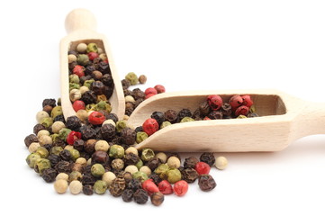Colored pepper on a wooden spoons isolated on white background