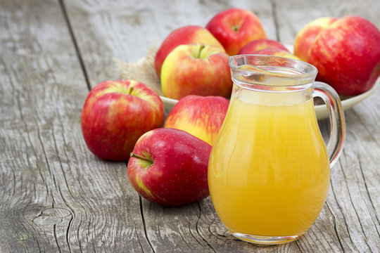 Apple juice and apples on wooden background