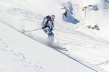 Skiing in the sunlight at high speed in a cloud of snow dust