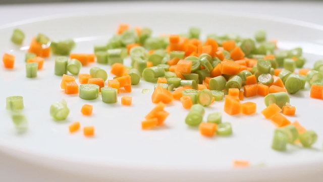 slicec carrot and green bean pices falling in white background