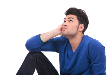 thoughtful young casual man sitting and looking up