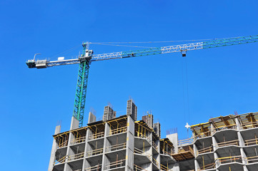 Crane and building construction site against blue sky