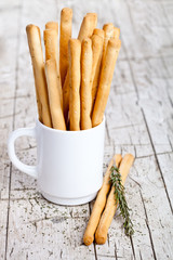 cup with bread sticks grissini and rosemary
