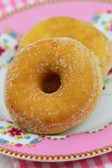 Ring doughnuts on pink plate, close up